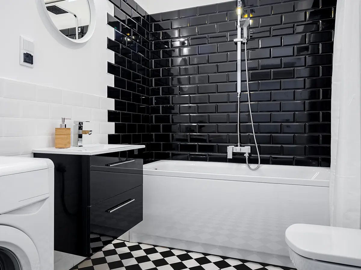 black and white bathroom with dark shower tiles and checkered tile flooring