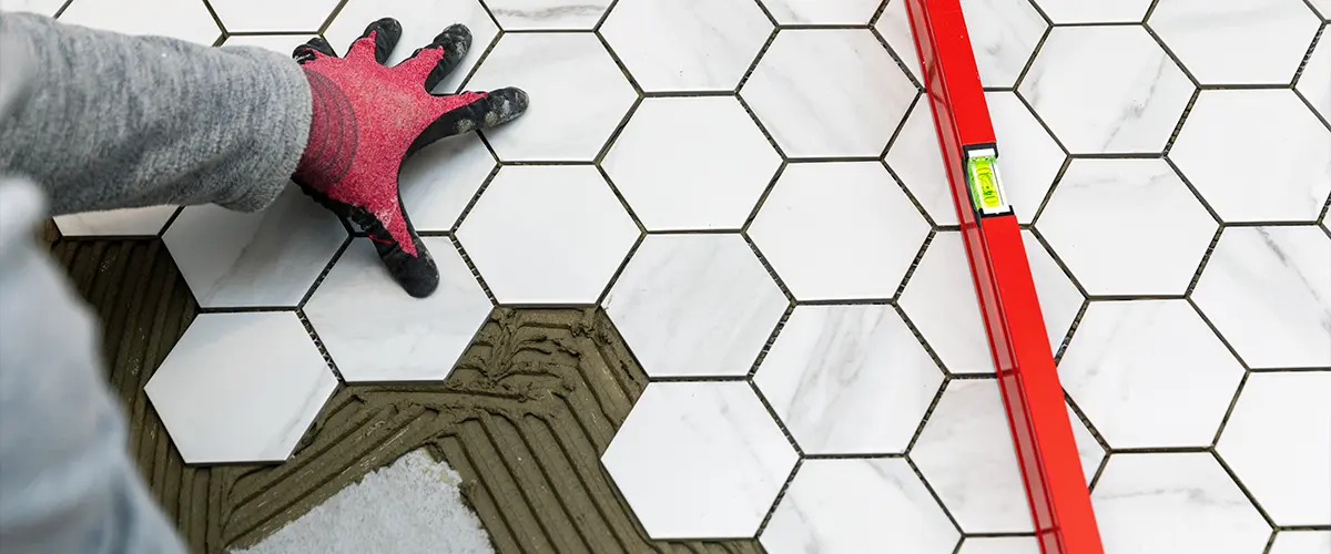 tiler laying marble texture hexagon tiles on the bathroom floor