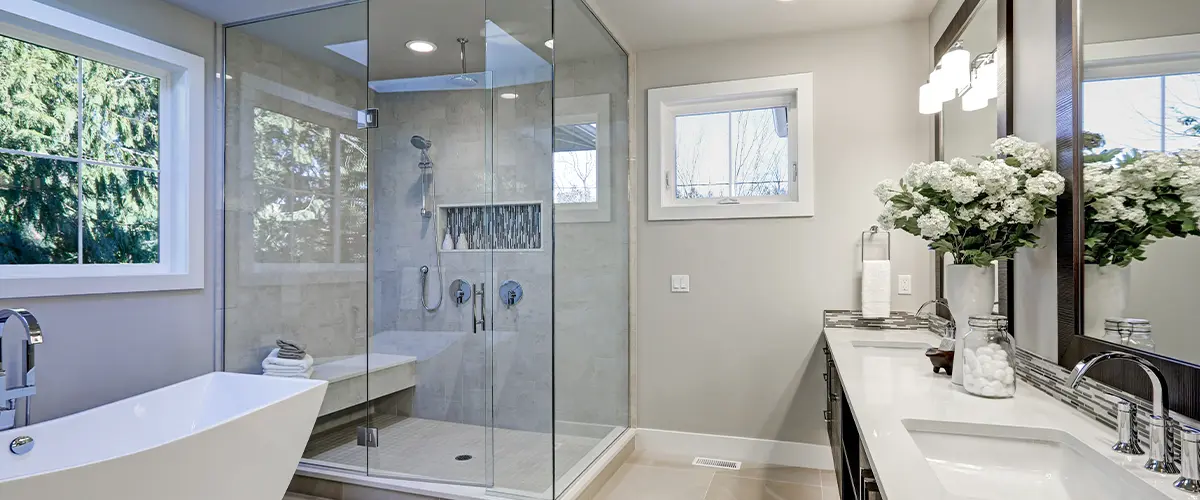 Luxury modern bathroom with glass walk-in shower, freestanding tub, double vanity, and skylight lighting